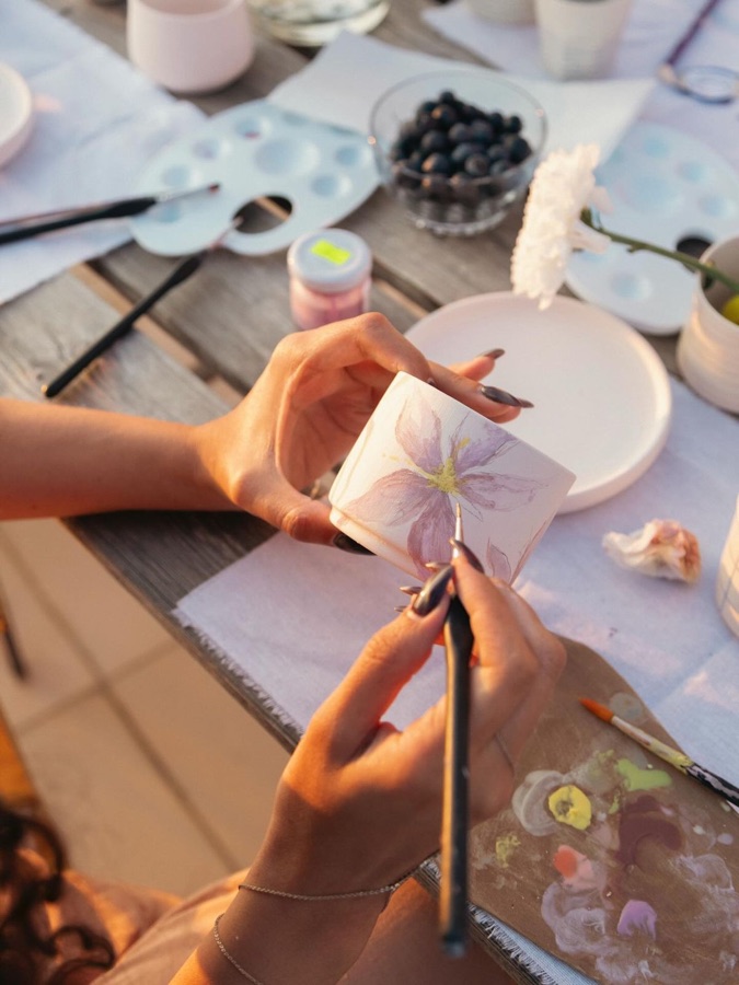 Mãos pintando uma peça de cerâmica no fim de tarde