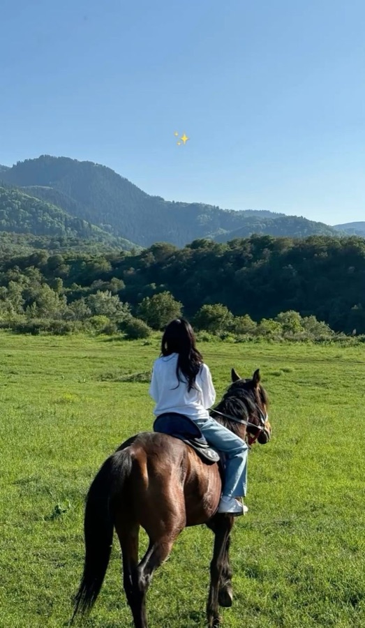 Mulher a cavalo em campo aberto entre montanhas